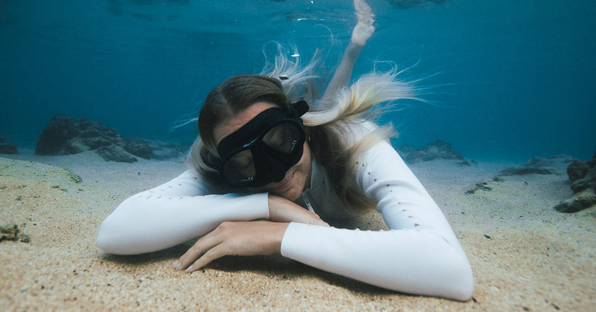 girl laying comfortably underwater wearing a long-sleeve swimsuit