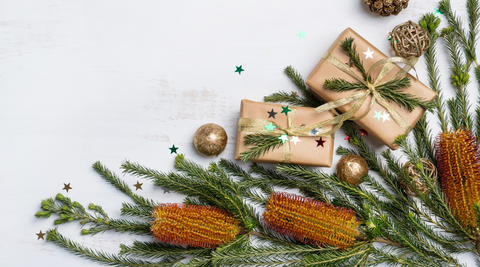 image of banksia flowers with pine needles, decorative brown paper packages wrapped up against a white background