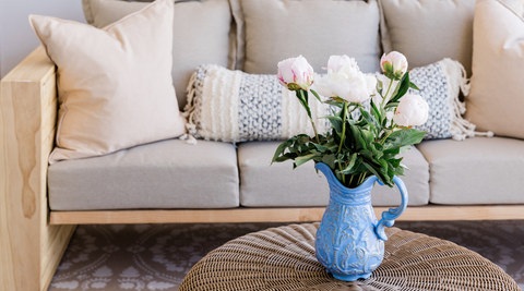 image of a living room couch with a coffee table and a blue jug with white blooms