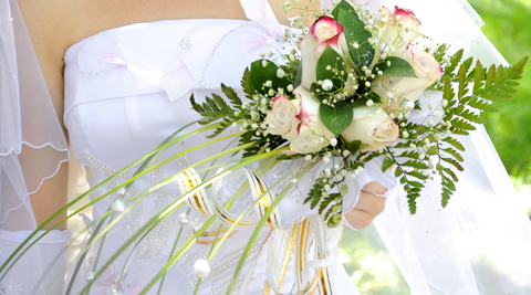 image of torso of bride in white beaded dress with green and cream bridal bouquet