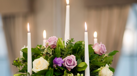 close up of lavender and white roses in green christmas flowers centrepiece with white lit candles throughout