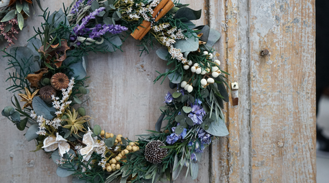 image of a christmas wreath with natives and muted colours of green, white, purple and brown on a faded timber door