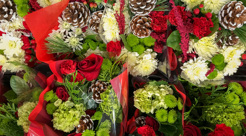 Christmas flowers arrangements of roses and pine cones and white mums wrapped in red and white plastic