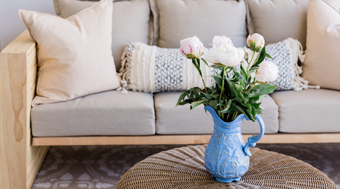 image of light grey couch with white pillows and a blue vase with white flowers for coastal-flower-style