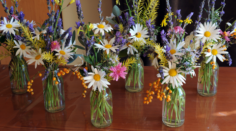 flowers including daisies in small bouquets in small glass vessels from a flower arranging party