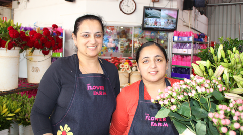 image of two flower farm female employees in the florist shop holding blooms