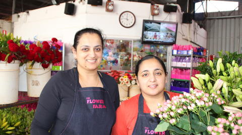image of two of our Flower Farm team in our workshop with a bouquet of yellow blooms