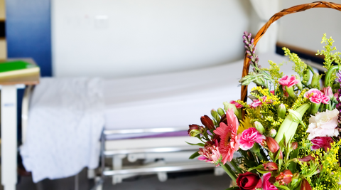 hospital bed in the background with a floral arrangement to the right in the foreground for flowers for a baby girl with hospital delivery