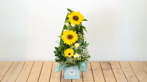 yellow gerberas arrangement in a square box on a wooden table for flowers with gifts delivery