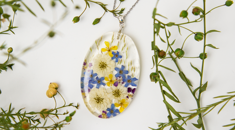 gel pendant with tiny yellow, blue and white flowers encased, and with green fronds around