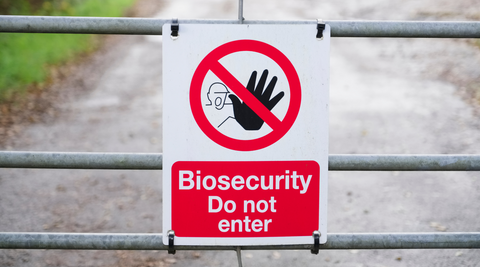 close up of a biosecurity sign with a hand with a red circle and red slash through it hanging on a fence for grown not flown flowers