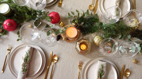 table scape with lots of christmas extras including rosemary, pine leaves, pomegranates and candles for how to make christmas flower arrangements