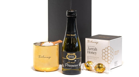 product image of black prosecco bottle with black label, cream and gold box of jarrah honey, two gold wrapped Lindt balls and a gold tin