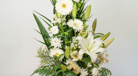 white lilies in bouquets arrangement also featuring roses and gerberas and foliage and pops of yellow