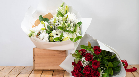 red roses arrangement and white floral arrangement on a wooden table demonstrating the skills and benefits of a local florist