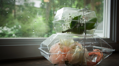 boutonnière and corsage flowers in clear plastic cases stacked up against a window