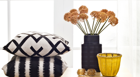 pillows with geometric patterns, black vase with yellow flowers and a yellow vase for traditional flower style
