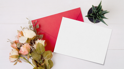 image of white card with red envelope next to dried flowers for valentine's day
