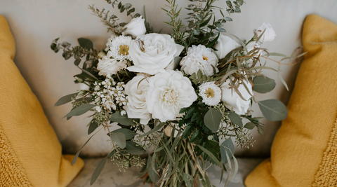 close up of white flower bouquet against white and yellow pillows