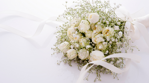 white roses in a wedding bouquet tied with a white satin ribbon on a white background