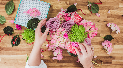 image of hands putting together a bouquet of fresh flowers with a polka dotted box to the left