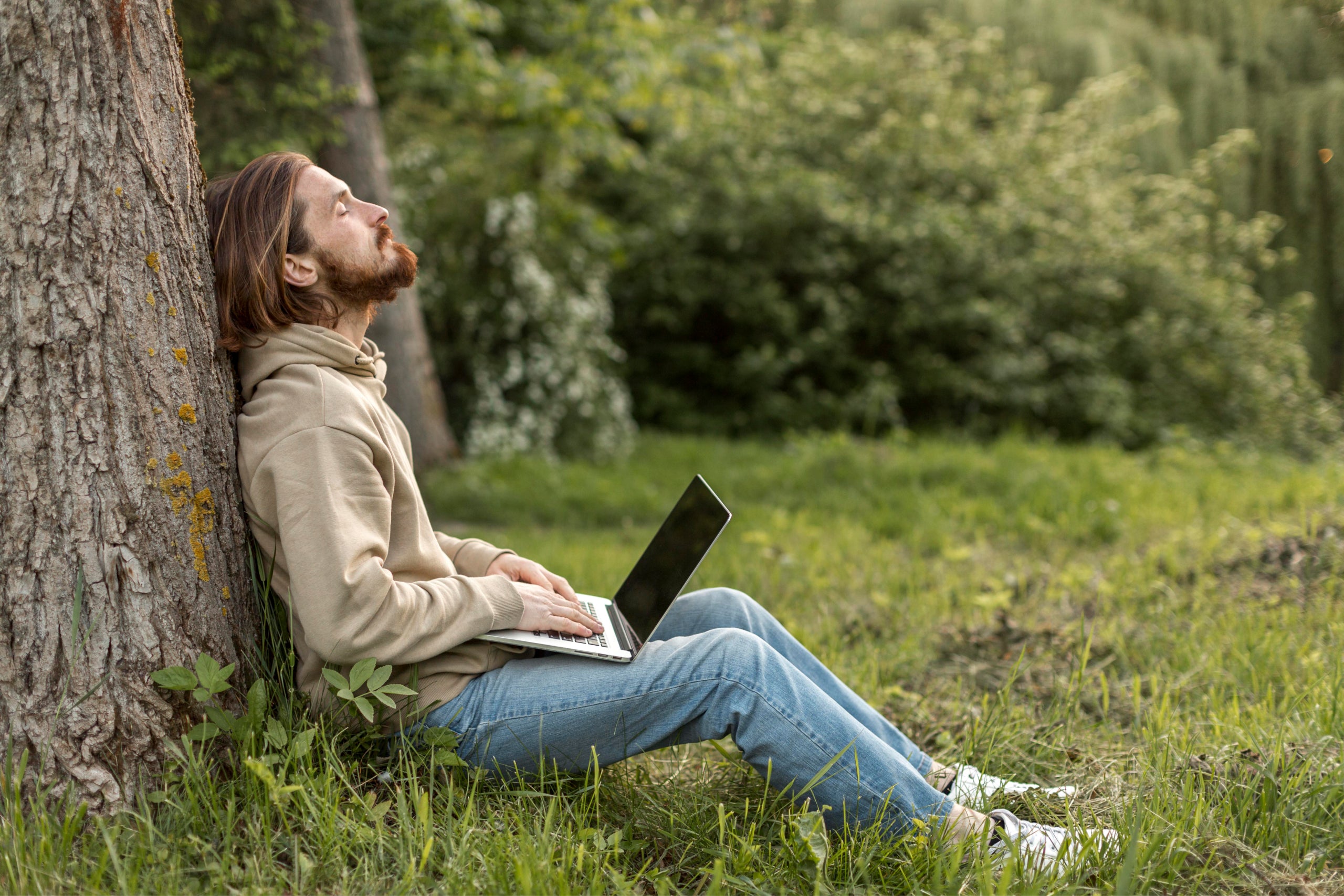 Side view of man in nature with laptop