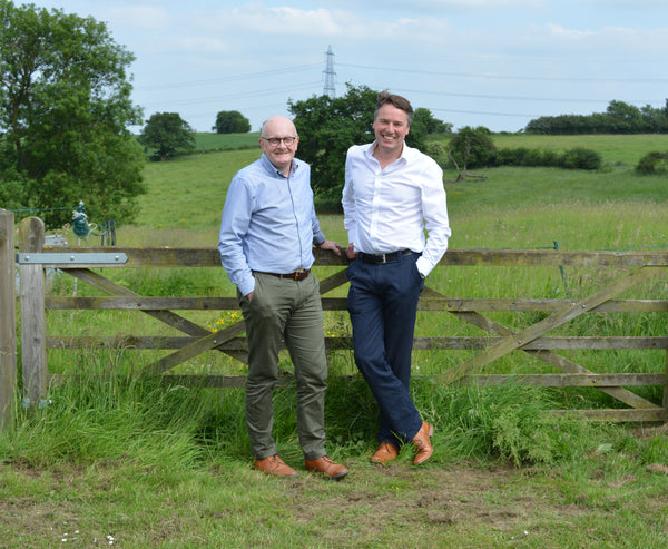 YuMOVE co-founders John Davies (left) and John Howie (right) standing by a gate with a field behind them