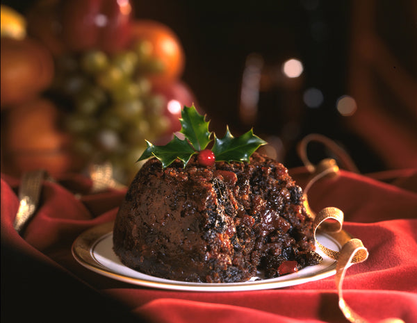 Plate of Christmas pudding with holly and berries on top