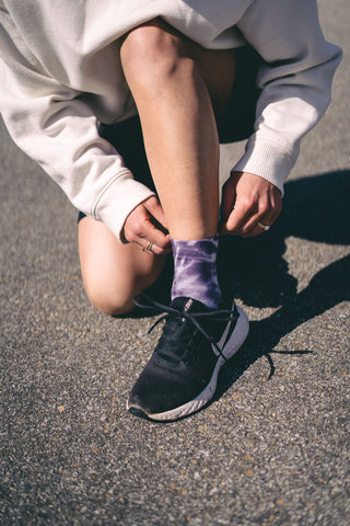 Girl on a run wearing black Nike running shoes and MERGE4's grey tie dye athletic quarter crew socks.