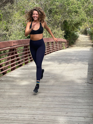 Girl wearing athletic running clothes while running outdoors on a bridge wearing Nike running shoes and MERGE4's Quarter Crew Running Athletic socks.