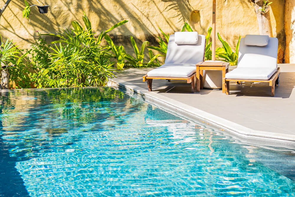 Two lounge chairs by a pool that has been well maintained with a swimming pool flow meter