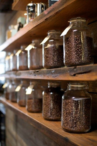 coffee beans stored and displayed in glass jars on wooden shelves