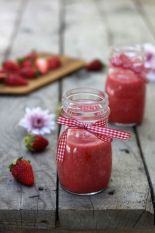 strawberry smoothie juice in glass jars on a wooden table