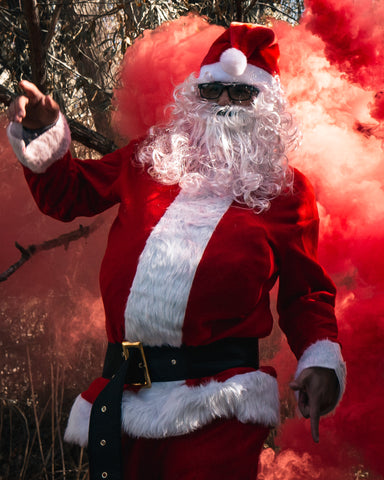 Santa Clause Photoshoot model surrounded with red smoke bombs