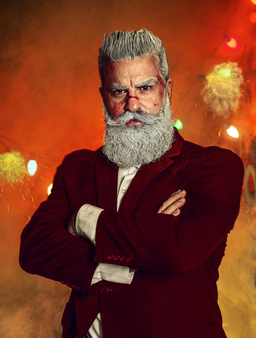 Sexy Santa posing in a nontraditional photoshoot surrounded by red and gold smoke