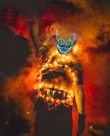 Costumed model posing in a Halloween inspired photoshoot surrounded by orange and red smoke from smoke bomb grenades