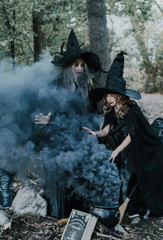 mother and daughter dressed as witches with black background smoke and smoky background