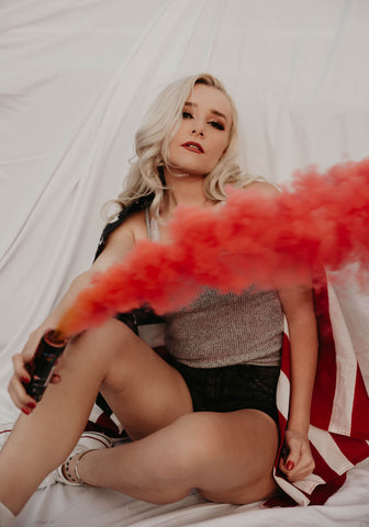 Girl with an American Flag draped on her and a red smoke bomb for July 4th