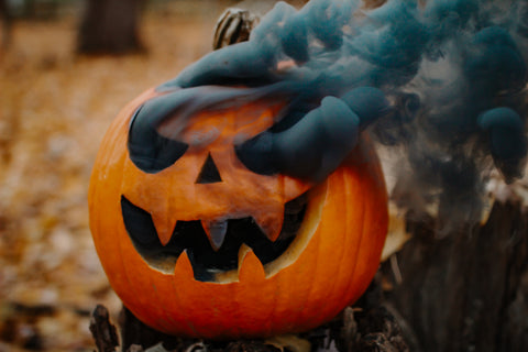 A pumpkin with black smoke and a colorful smoke background