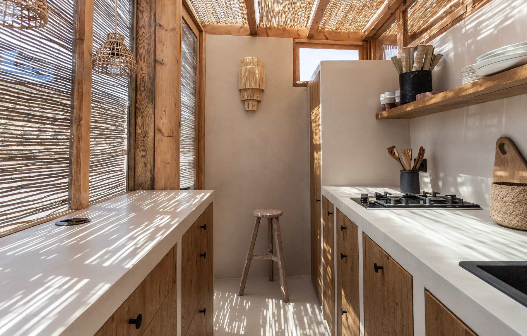 scandinavian style modern mini kitchen with microcement surfaces and wooden cabinets and cane pergola ceiling