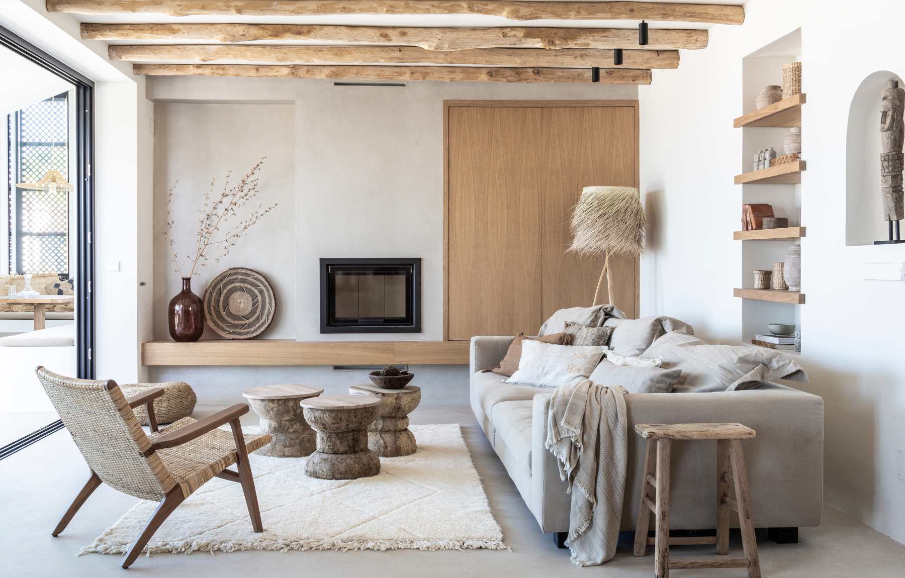 scandinavian style living room with wool rug, neutral tones, rattan lounge chair, wooden beams and rustic funiture and home decor