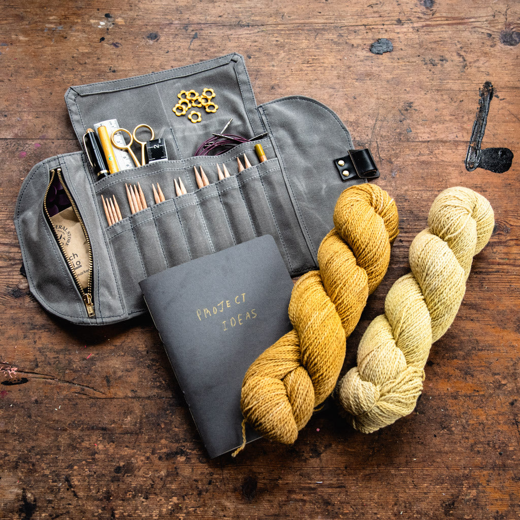 waxed canvas storage case filled with knitting needles, stitch markers, and other tools