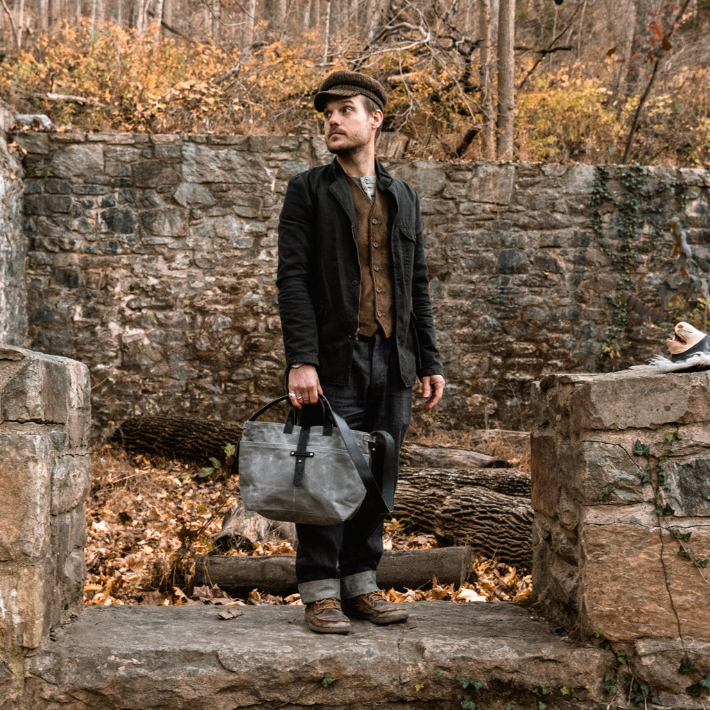 Man holding grey gender-neutral waxed canvas tote