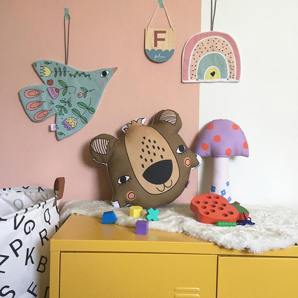 A gorgeous scandi style kids bedroom featuring a bear pillow and cute bird and rainbow wall hangings
