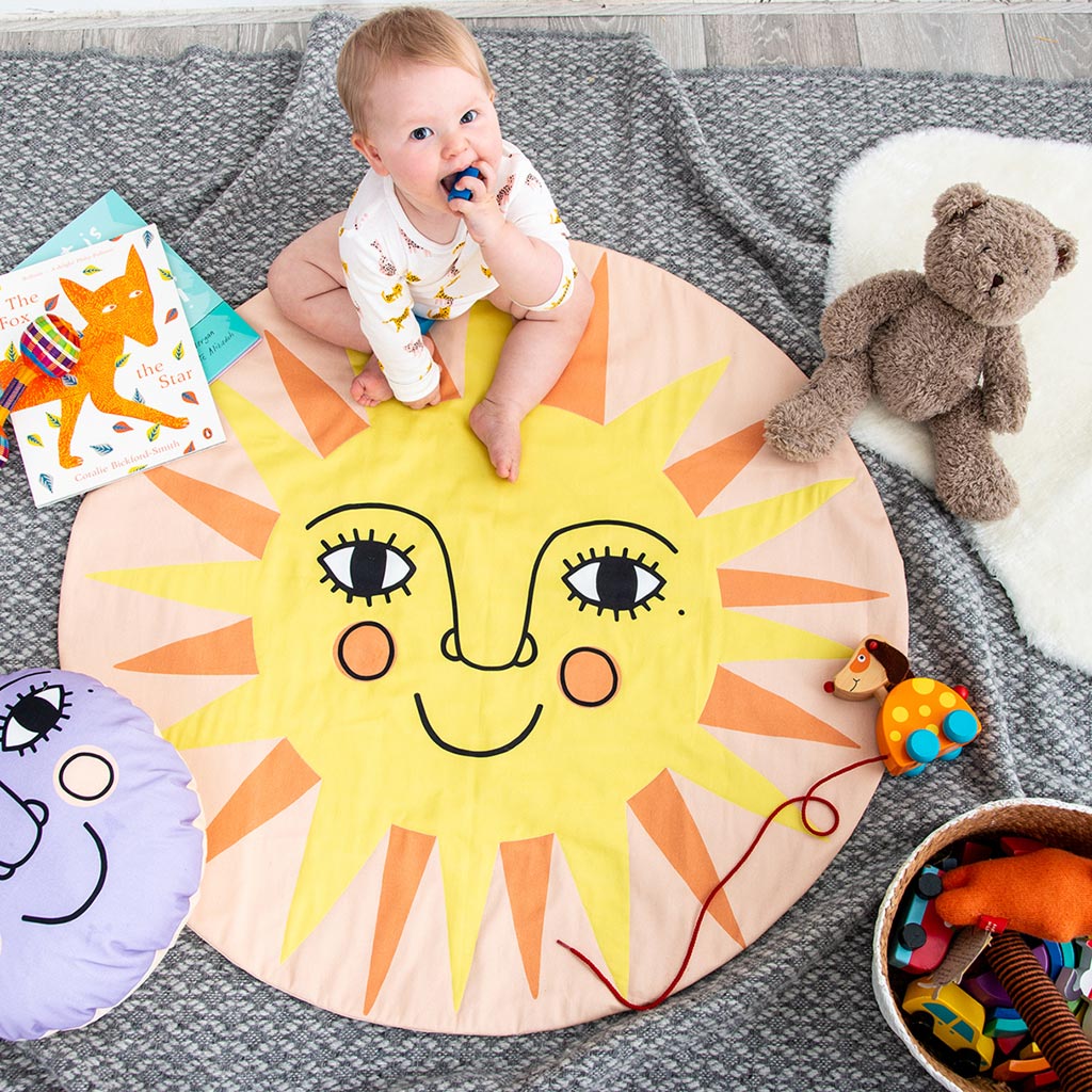 A round baby play mat with a smiley sun on it