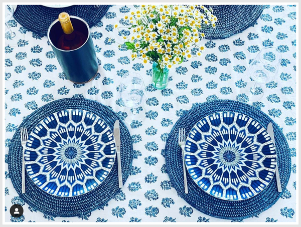 A dining table decorated with a blue-white set of plates and flowers.