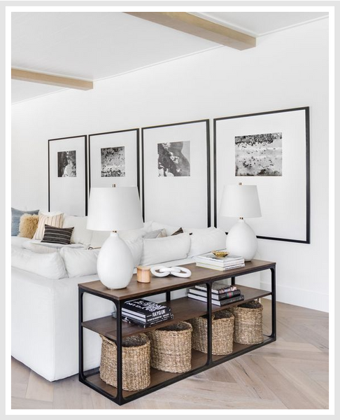 Side table with baskets stored at the bottom, white sofa and wall art in the background