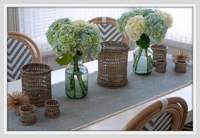 Rustic table decor with flowers, grey table runner, and candle holders.