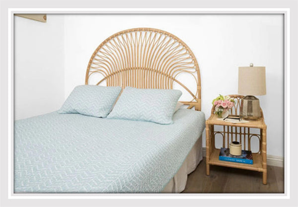 Bedroom with a bed, rattan headboard and bedside table.