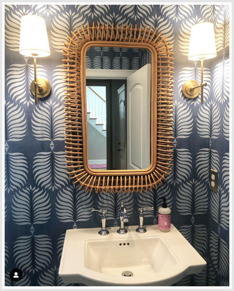Woven mirror in a blue wall bathroom above a sink.